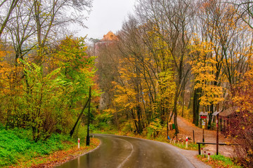 Autumn scenery of winding road, colorful trees and Pieskowa Skala castle in Ojcow National Park, Poland