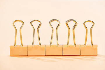row of paper clips on beige background