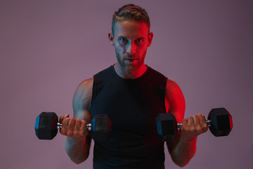 Concentrated young sports man make exercises with dumbbells.