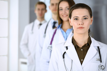 Fototapeta premium Doctor woman happy and cheerful while standing with colleagues in hospital office. Perfect medical service in clinic. Medicine and healthcare concept