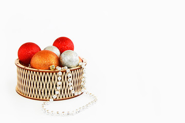 shiny multi-colored Christmas balls toys in a decorative wooden basket for the New Year holiday