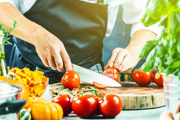 Koch schneidet frische rote Tomaten in Restaurant küche 