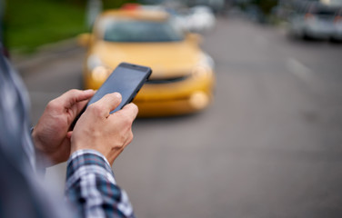 Man holding phone in his hands on blurry background taxi