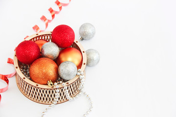 shiny multi-colored Christmas balls toys in a decorative wooden basket for the New Year holiday
