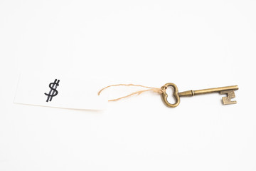 Old vintage brass key with dollar sign tag on white background