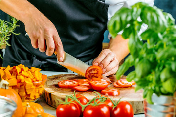 Koch schneidet frische rote Tomaten in Restaurant küche 