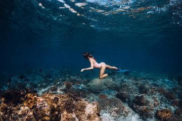 Slim woman freediver glides over bottom in underwater
