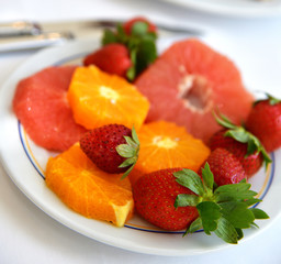 Strawberries and slices of orange and grapefruit on a plate