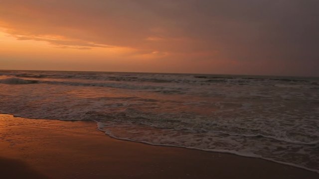 Pan shot of sea coast at dusk, golden sunset contrasting evening shadows