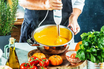 Chefkoch mit stabmixer kocht leckere kürbissuppe