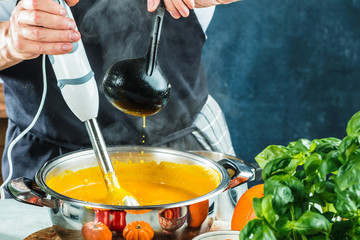 Chefkoch mit stabmixer kocht leckere kürbissuppe