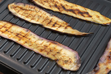 Fried eggplant or aubergine on electric grill, top view. Grilled vegetarian vegetables. Close up