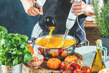Chefkoch mit stabmixer kocht leckere kürbissuppe