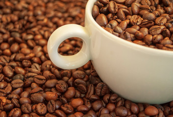 cup with coffee beans and cinnamon sticks	