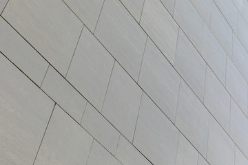Low angle view of wall with gray smooth tiles of different shape (rectangular and square).