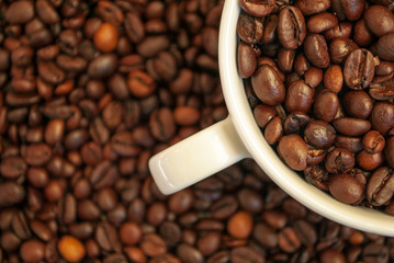 cup with coffee beans and cinnamon sticks	