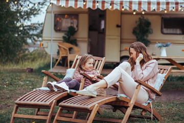 Happy family - mother and little daughter relaxing and having fun in countryside on camper van...