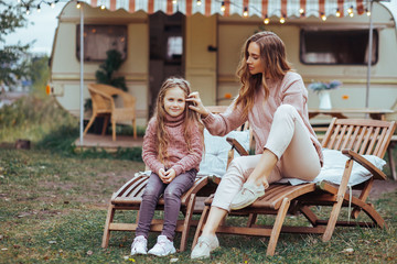 Happy family - mother and little daughter relaxing and having fun in countryside on camper van...