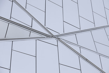 Close-up of junction of metal lines on white tiled wall of building