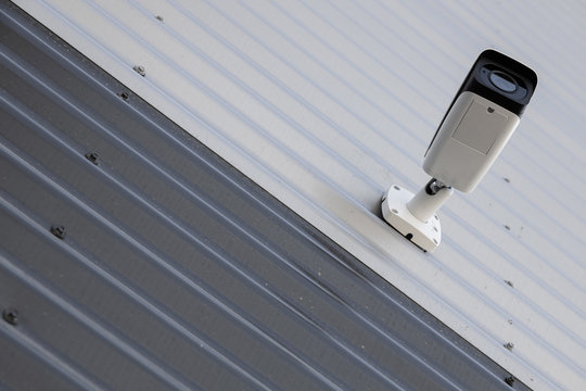 Bottom view of high-tech black and white video monitoring camera on black and white corrugated wall