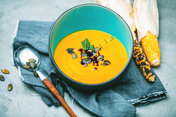 close-up view of pumpkin soup puree in bowls, corn and pumpkins on table