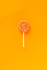 Bright orange striped with white lollipop on an orange-yellow paper background. Bright banner for...