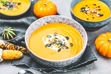 close-up view of pumpkin soup puree in bowls, corn and pumpkins on table
