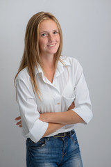 portrait of a young beautiful girl in a white shirt and jeans on a gray background