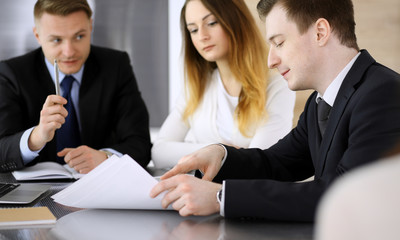 Business people or lawyers discussing questions at meeting in modern office. Unknown businessman and woman with colleague sitting and working at the glass desk. Teamwork and partnership concept