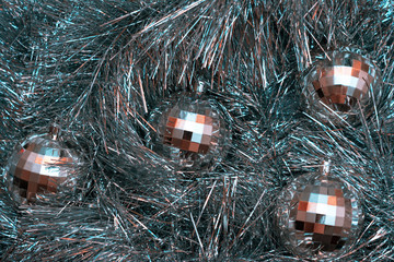 Christmas toys in the form of disco balls lie on a festive silver tinsel, top view