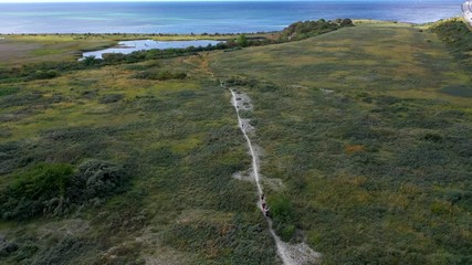 People running trail race along coastal hiking route, aerial view pan