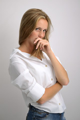 portrait of a young beautiful girl in a white shirt and jeans on a gray background
