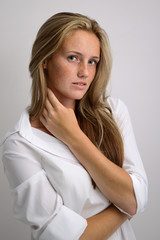 portrait of a young beautiful girl in a white shirt and jeans on a gray background