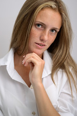 portrait of a young beautiful girl in a white shirt and jeans on a gray background