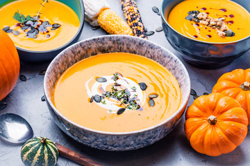 close-up view of pumpkin soup puree in bowls, corn and pumpkins on table