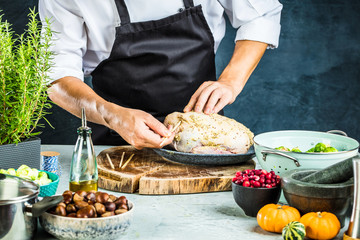 partial view of male chef in apron preparing stuffed duck