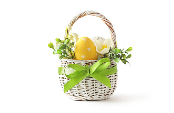 colorful easter eggs and spring flowers in basket isolated on white background