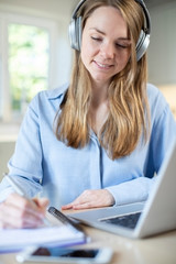 Woman Studying At Home Using Laptop And Wearing Headphones