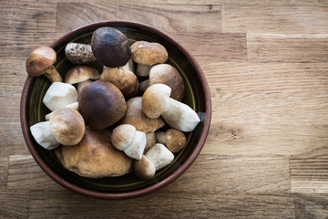 Porcini (boletus edulis) in a bowl on wooden table - high angle view