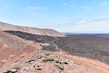 Black lava field in the bizarre volcanic landscape of Timanfaya National Park on a sunny day. Lanzarote, Canary Islands, Spain 