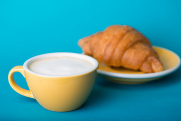 yellow cup with croissant on a blue background