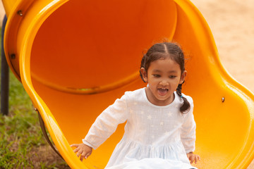 Asian girl plays a slider on the playing field, creating development