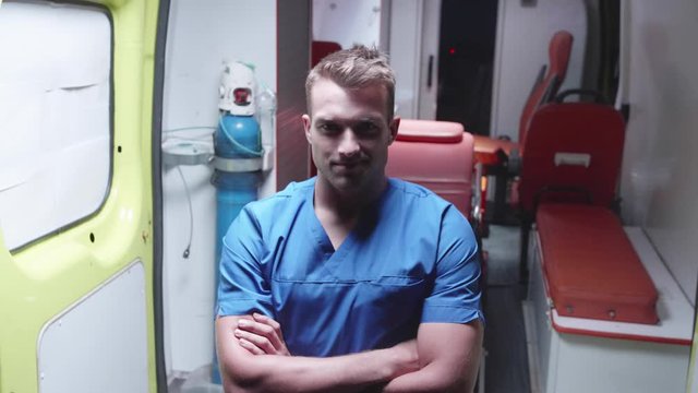 Happy corpsman stand on the background of ambulance car.