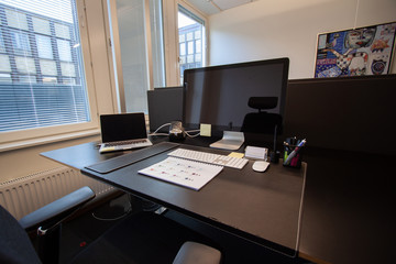 Office desk with color samples on white paper. Laptop with external screen.