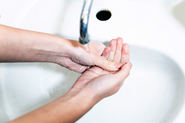 Washing your hands under running tap water.