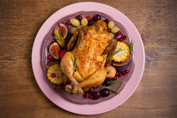 Whole roast chicken or turkey with fruits, vegetables and berries, wooden table. Overhead, horizontal