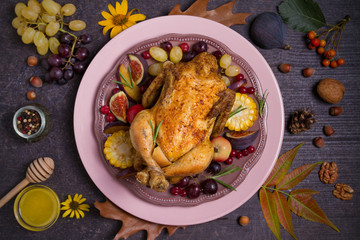 Whole roast chicken or turkey with fruits, vegetables and berries. Autumn decorations on the table. Autumn food background, flat lay