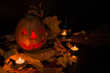 Naklejka premium The Concept Of Halloween. Jack's lantern carved from a pumpkin, candles, witch's broom, autumn leaves on a black background.