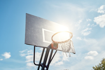 Fototapeta na wymiar Photo of basketball hoop against blue, cloudy sky on summer day.