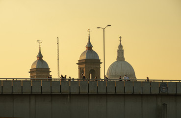 Long shot of pedestrians crossing London Bridge at sunset